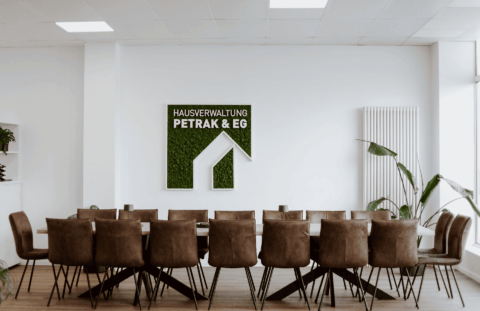 Der Besprechungsraum mit großem Tisch, vielen Stühlen und dem Firmenlogo an der Wand.